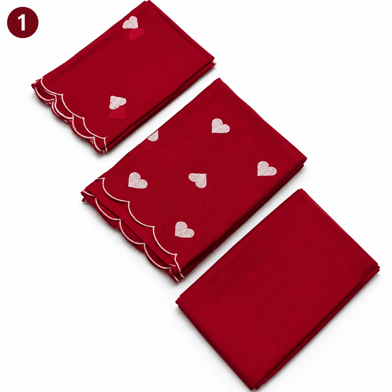 Folded red saree fabric set with white heart motifs and scalloped embroidered border