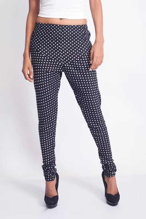 Front view of navy polka dot leggings with a slim fit and ruched hems, styled with black heels