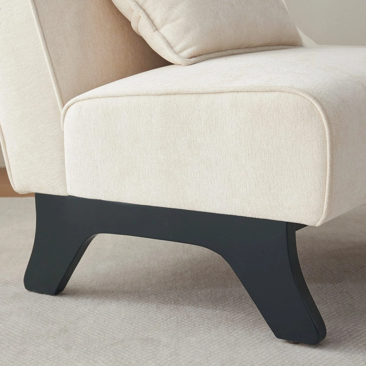 Close-up of the cream upholstered seat corner and dark wood leg base detail