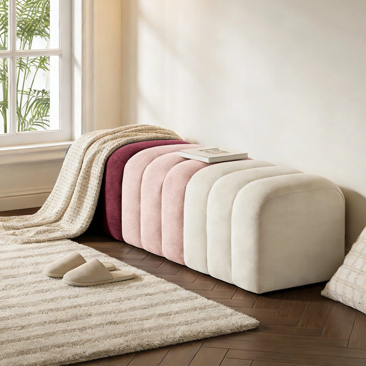 Angled side view with a throw and book on top, highlighting the curved end and plush upholstery