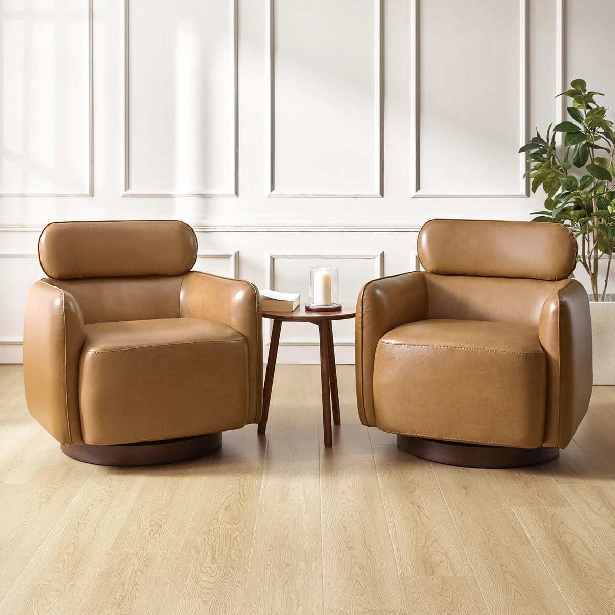 Two tan swivel accent chairs styled beside a small round side table