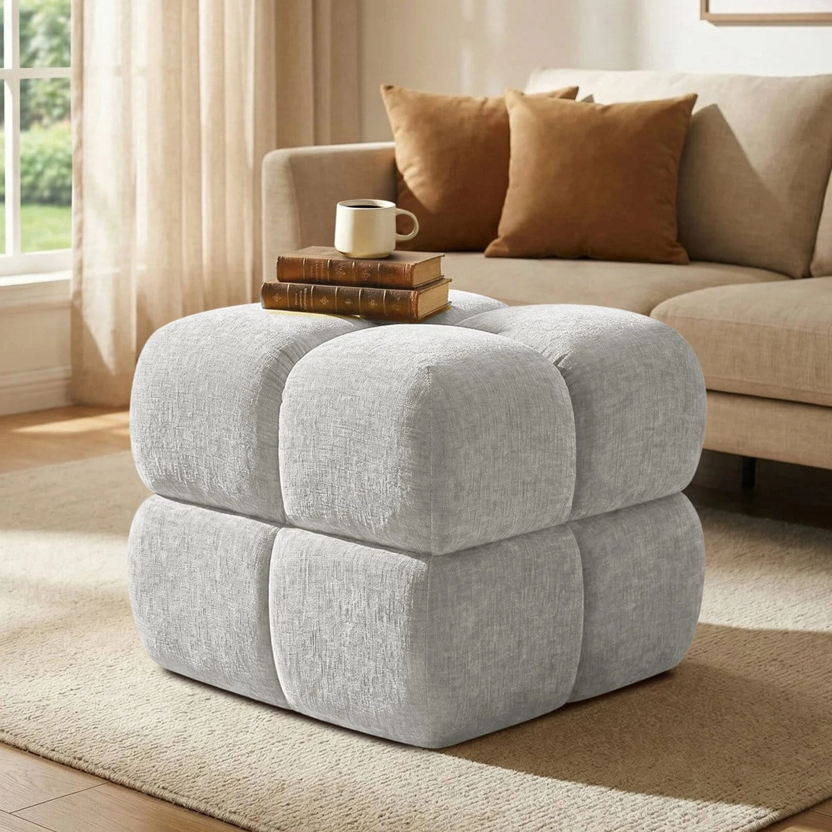 Ottoman styled as a side table with stacked books and a mug in a living room setting