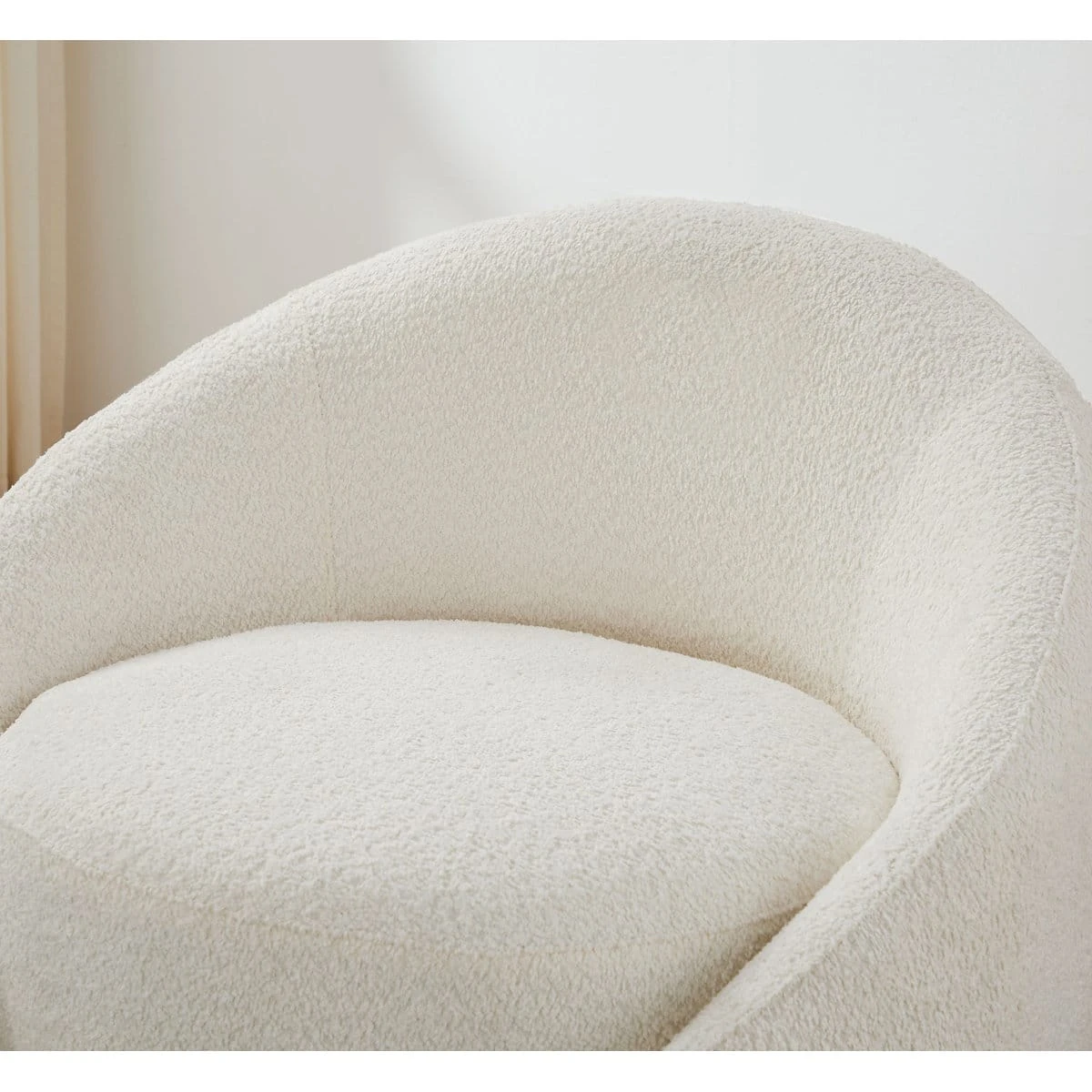 Close-up of the plush cream boucle upholstery on the backrest and round seat cushion