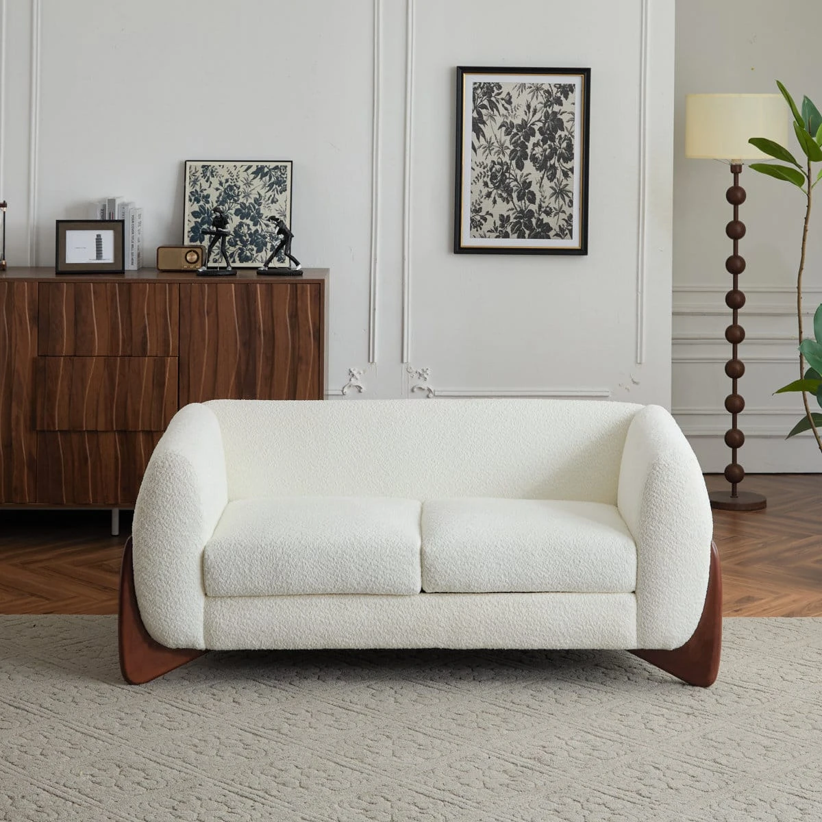 Front view of ivory boucle loveseat with curved arms and dark wooden side legs in a styled living room
