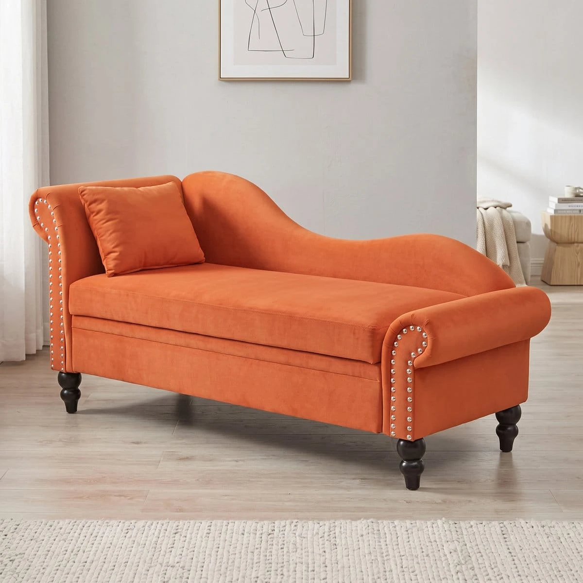 Angled room view of the orange chaise bench showing full silhouette and decorative studded arms