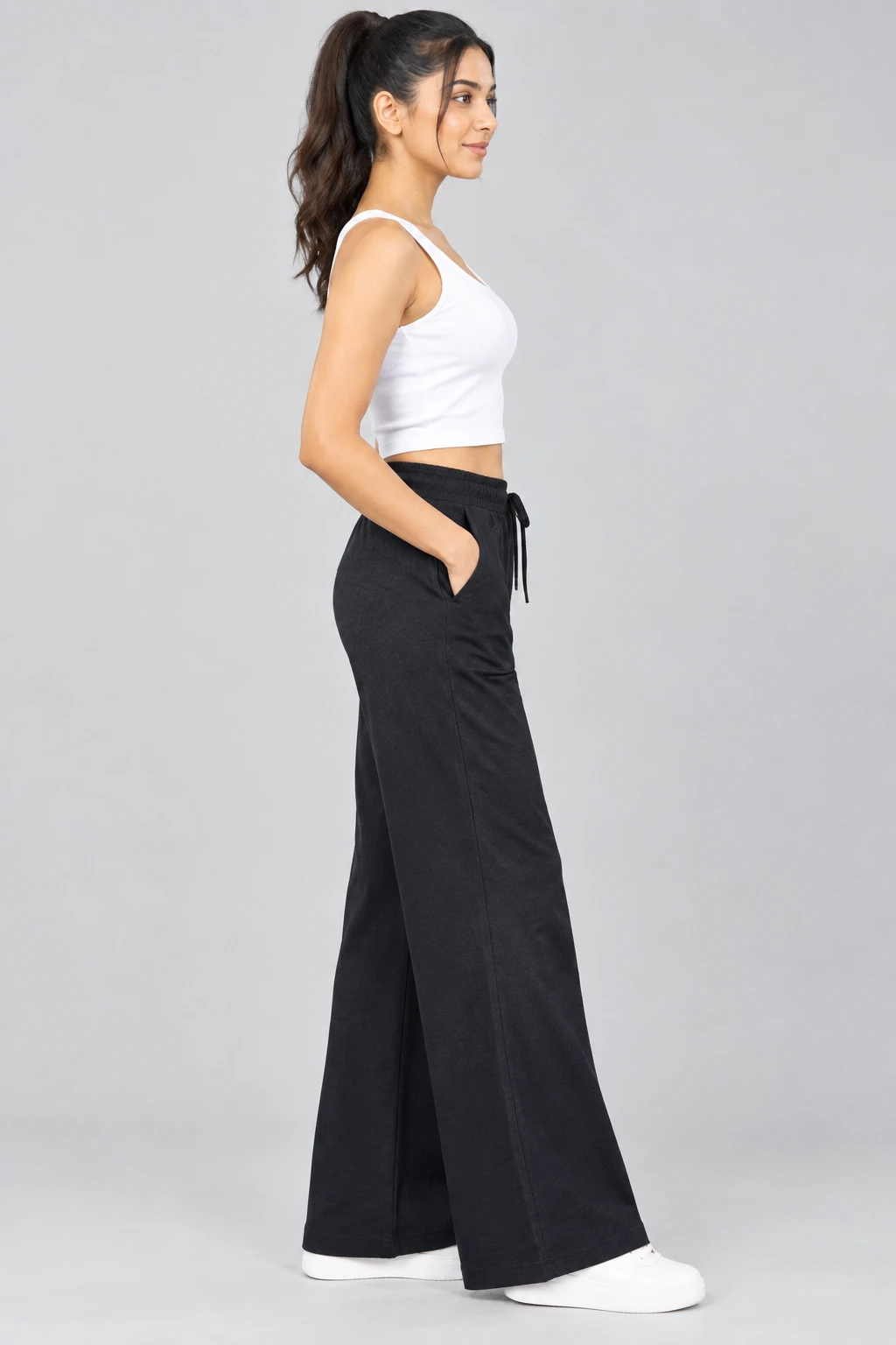 Side profile highlighting the draped wide-leg fit, elastic waistband and pocket of the black lounge pants