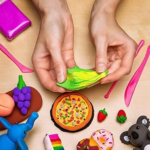 Hands stretching green and yellow clay on a table beside pink tools and finished mini clay figures
