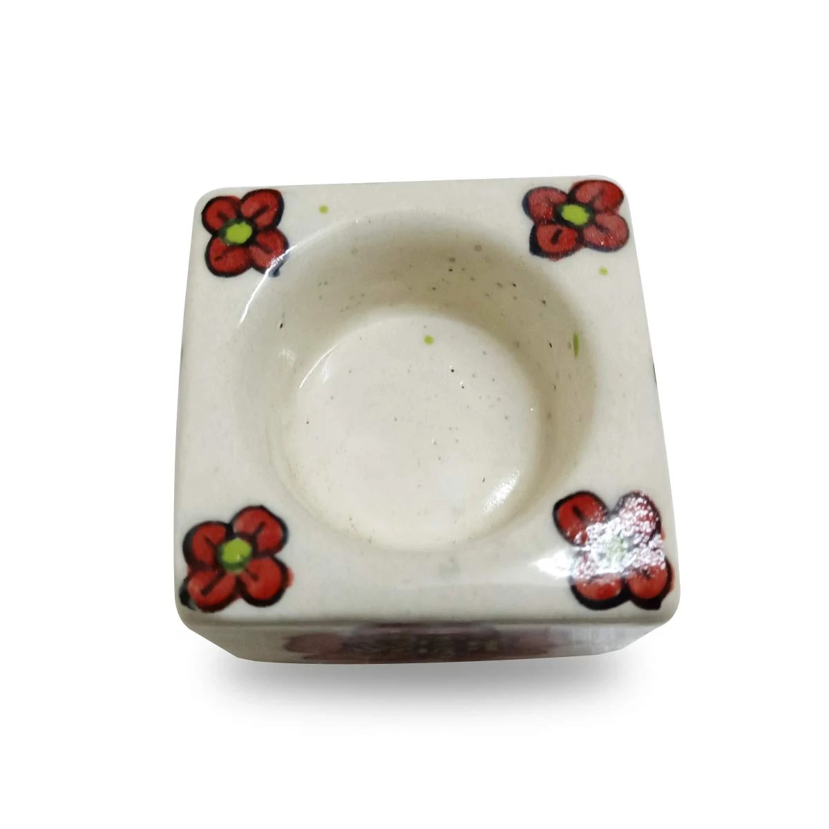 Top view of one empty ceramic tealight holder showing the recessed candle cup and floral corner details