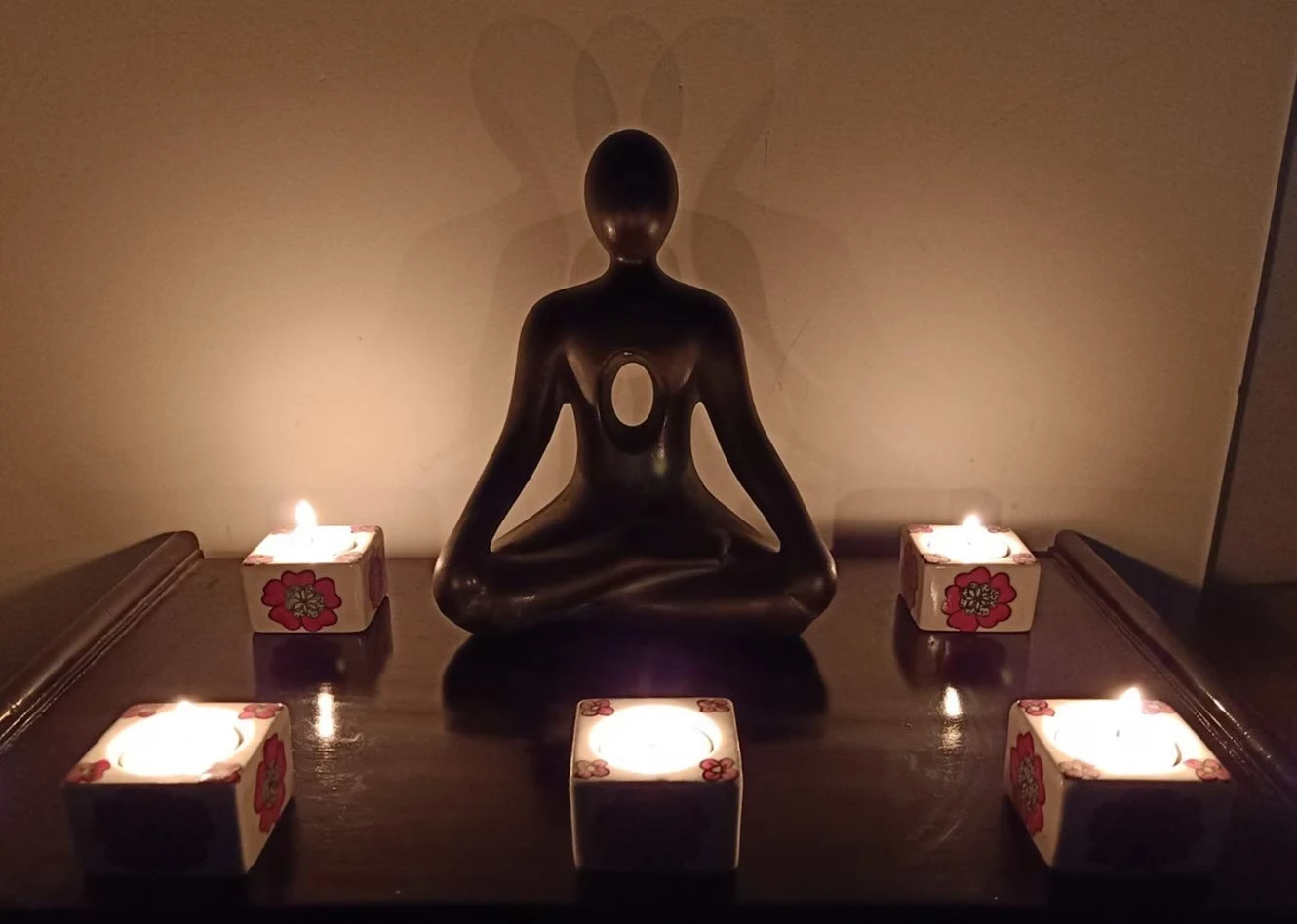 Five cream ceramic cube tealight holders arranged together, each with red flower motifs and white tealights