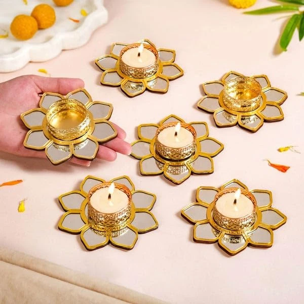 Hand holding one gold lotus tealight holder beside five matching holders on a styled tabletop