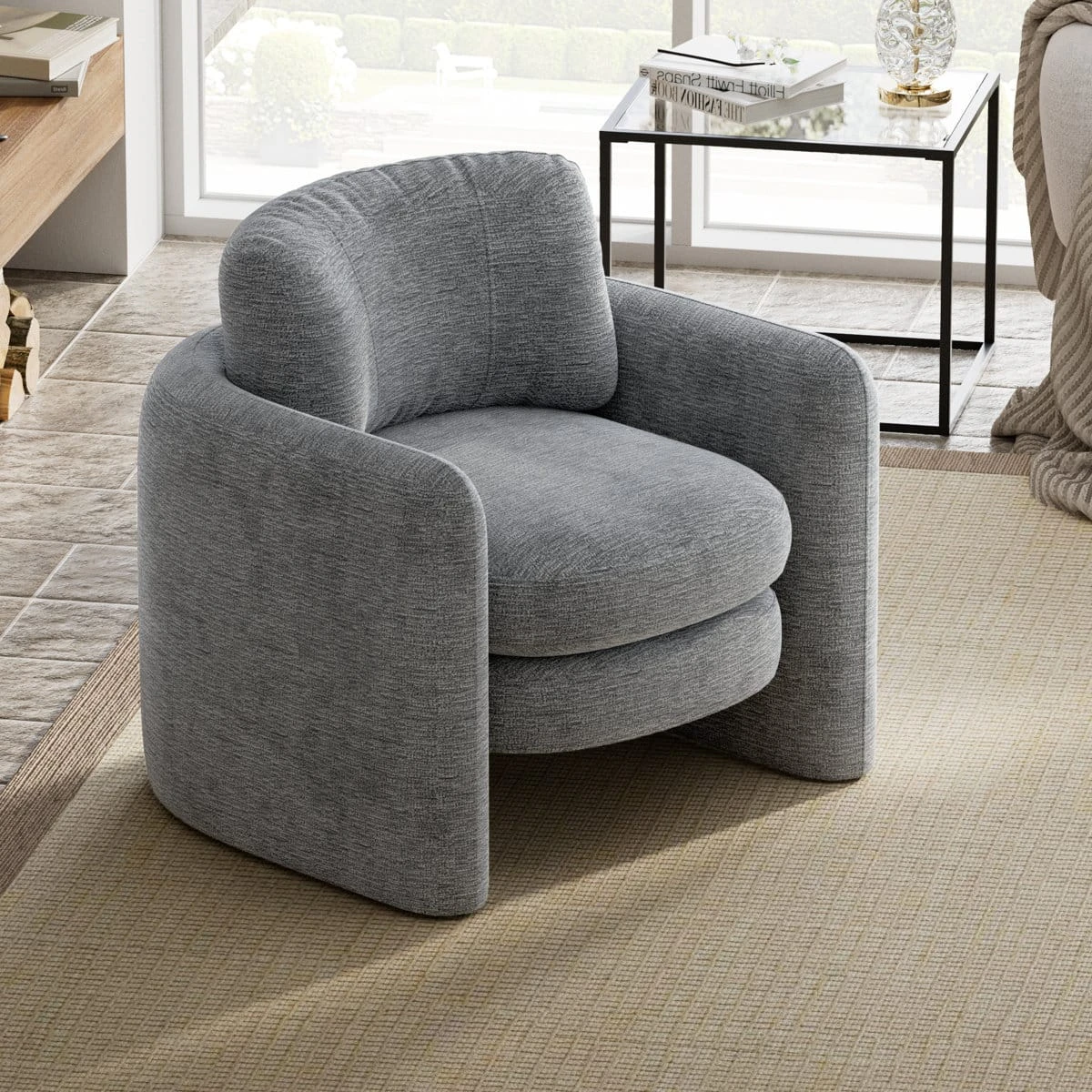 Front three-quarter view of the grey curved armchair beside a black metal side table
