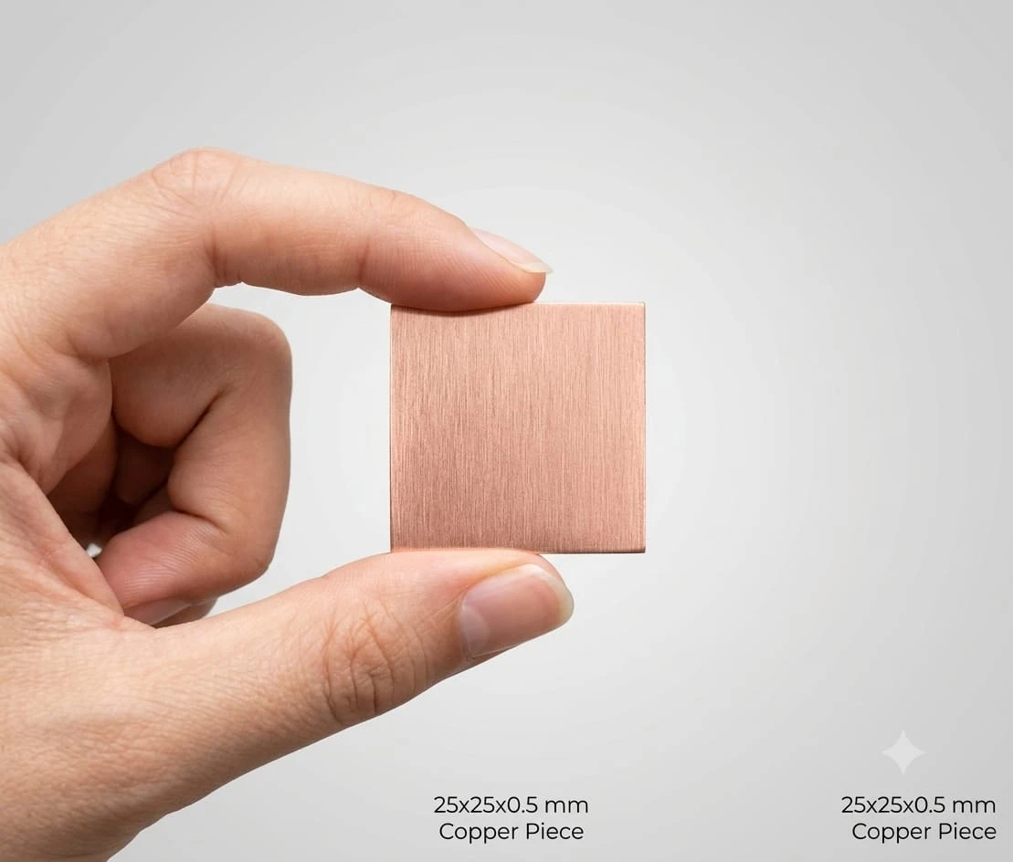Hand holding a 25x25x0.5 mm  copper square piece with size text on a light gray background