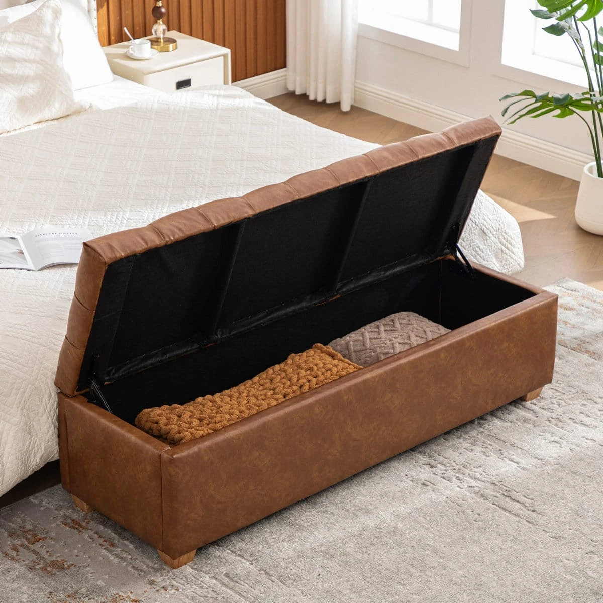 Brown faux leather storage bench with lift-up lid and blanket storage at the foot of a bed