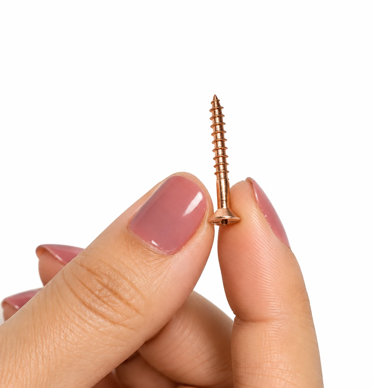 Copper-finish slotted countersunk screw pinched between fingertips, showing its small size and pointed tip