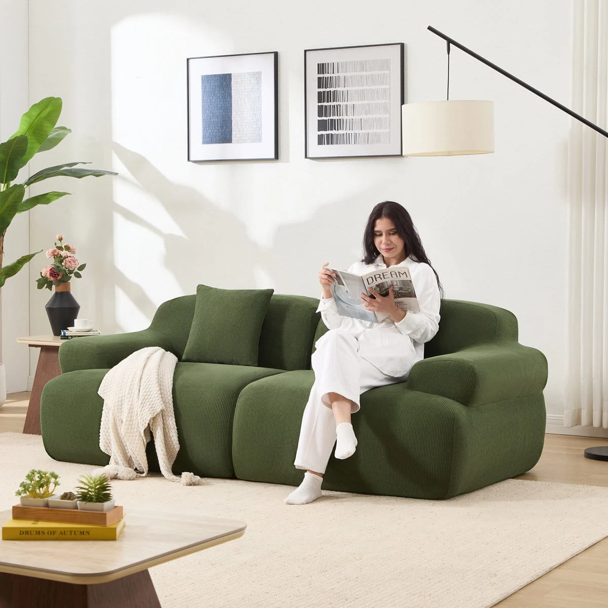 Olive green sofa shown in a living room with a seated model reading, highlighting spacious seating