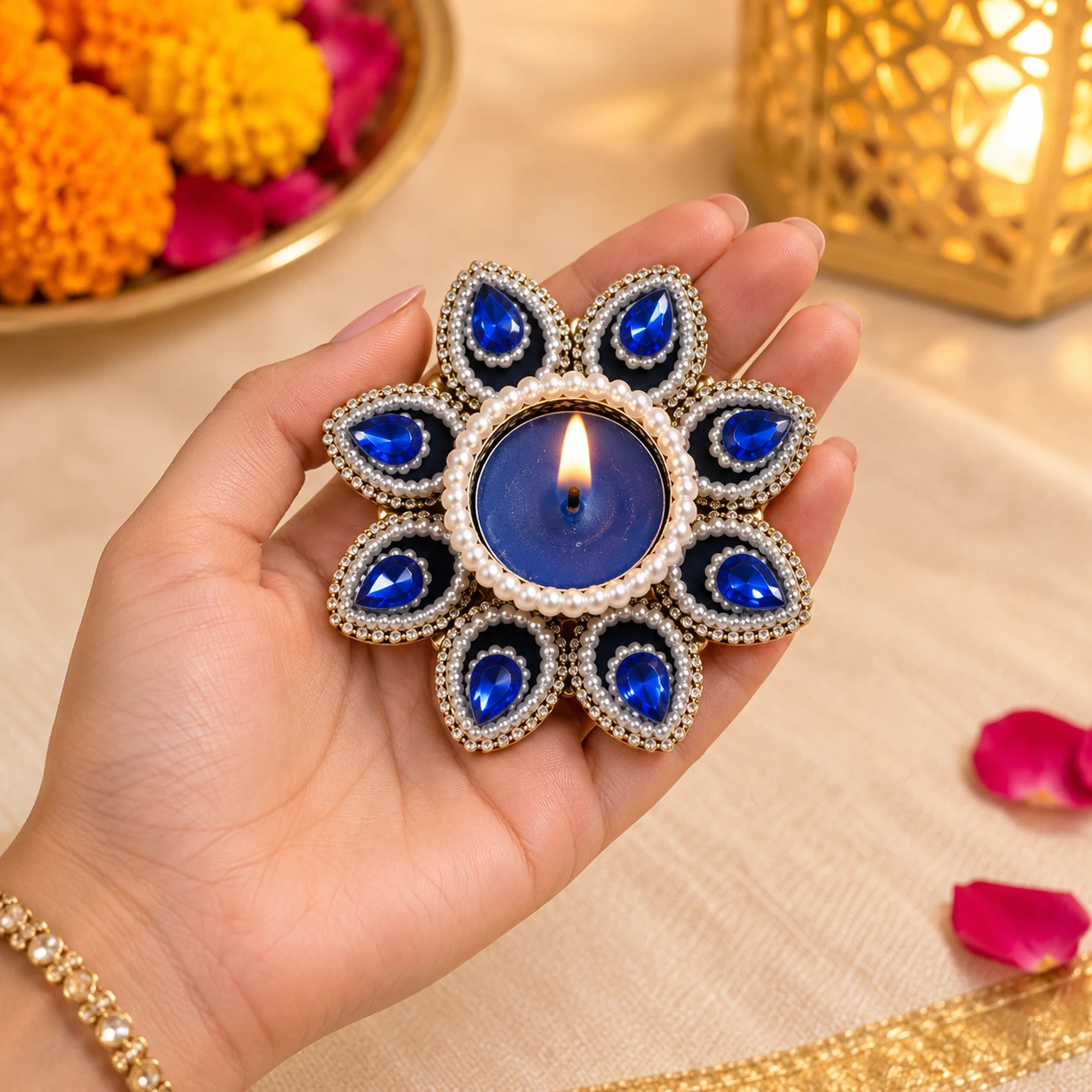 Hand holding a lit blue tealight holder showing floral gem design and compact size