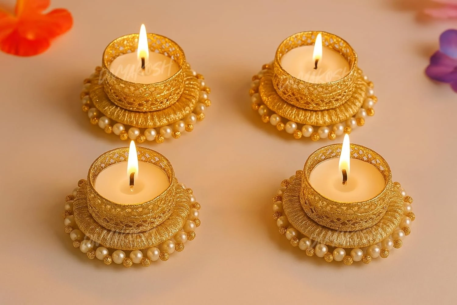 Top view of four lit gold tealight holders showing filigree rims and pearl-trimmed round bases