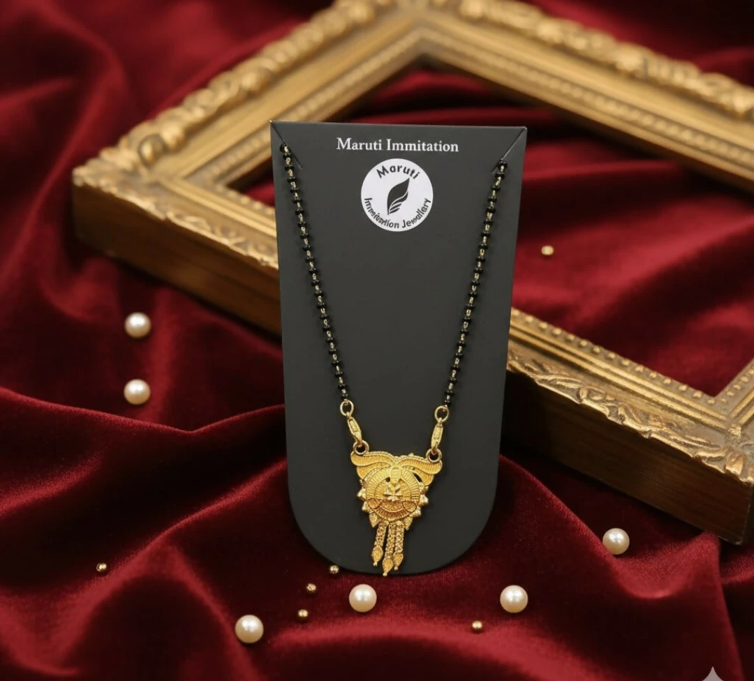 Mangalsutra displayed on black card against red satin with pearls and a decorative frame
