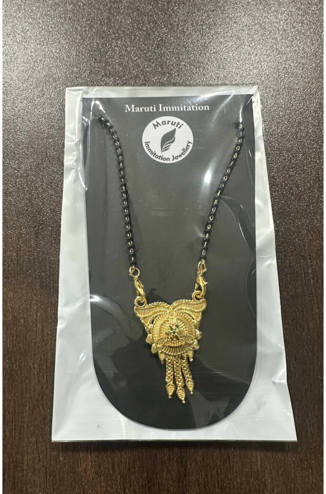 Packaged mangalsutra sealed in clear plastic, showing black beads and detailed pendant