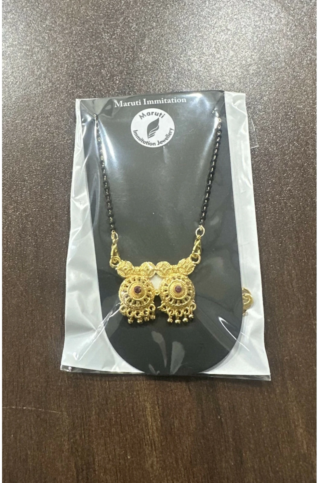Necklace sealed in a clear plastic sleeve on branded card, showing packaging presentation