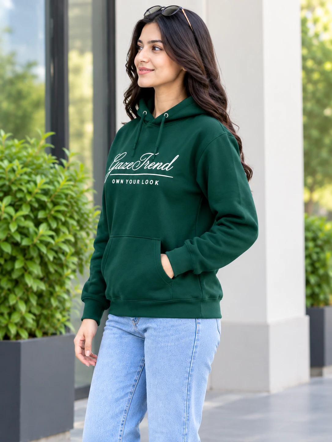 Side-angle view of dark green pullover hoodie showing pocket and relaxed fit