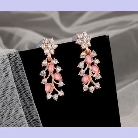 Close-up of matching drop earrings on black display, showing pink marquise stones and crystal flower tops