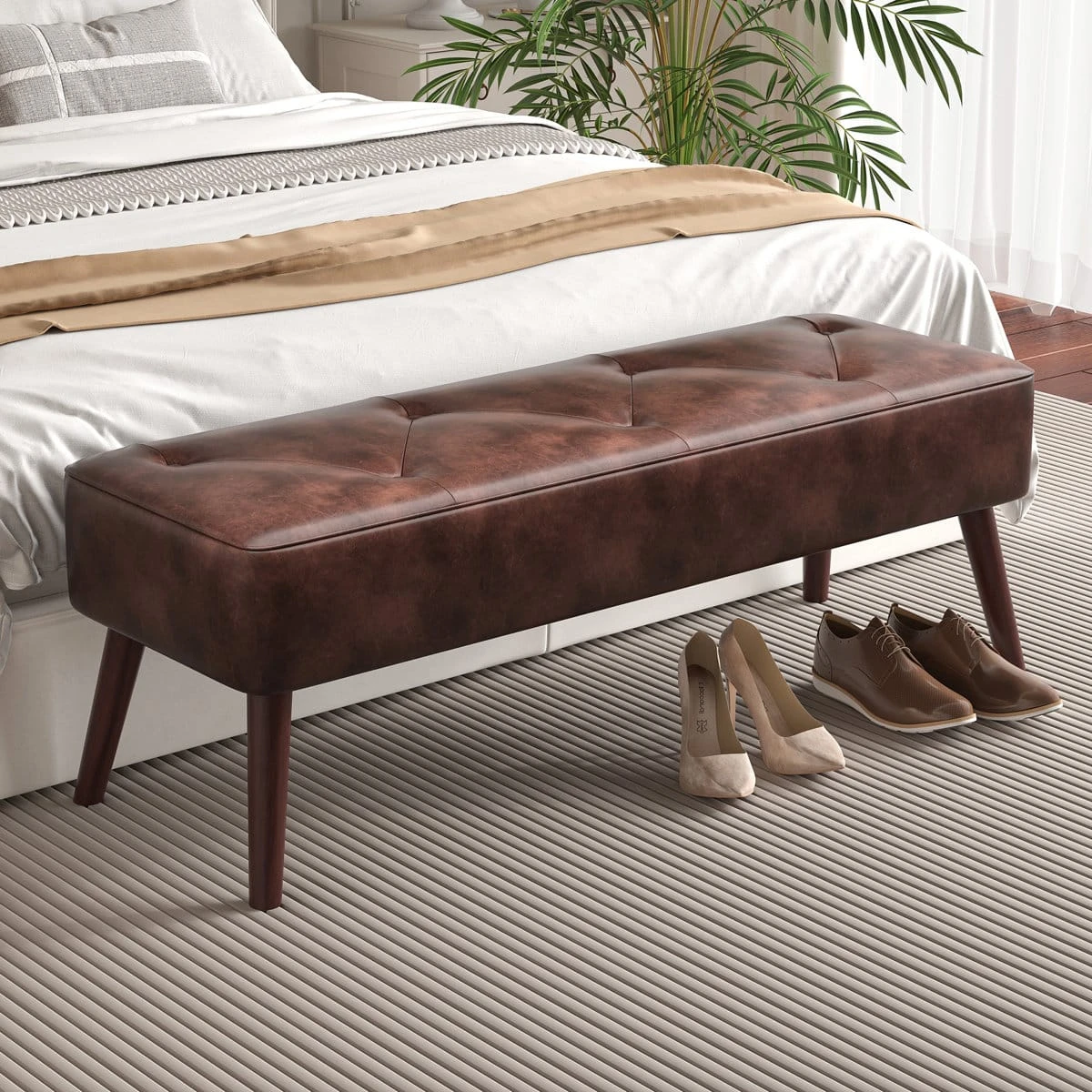 Side-angled bedroom view of the bench with shoes nearby, showing foot-of-bed placement