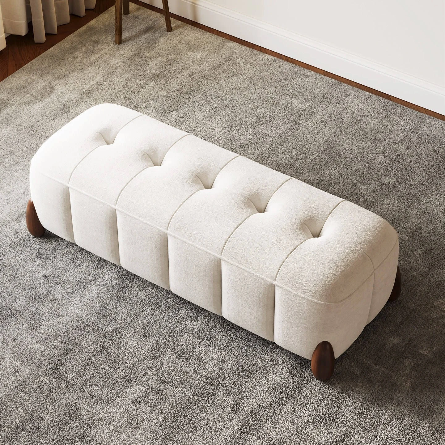 Top angled view of the cream tufted ottoman showing five button tufts and rounded ends