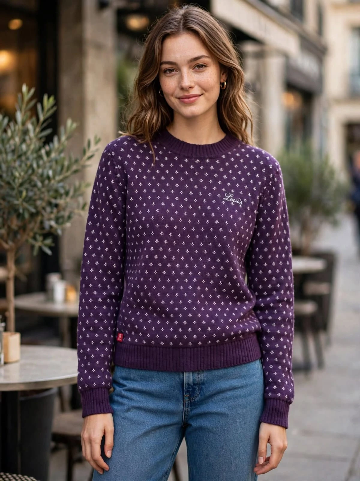 Close-up of the purple printed crewneck sweater on a model, showing ribbed trim and small Levi's chest logo