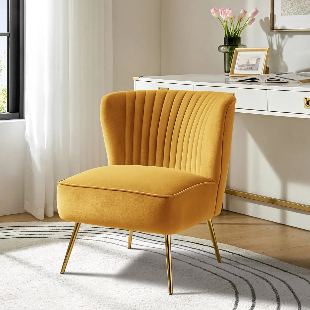 Mustard yellow velvet accent chair styled beside a white desk with gold legs on a patterned rug