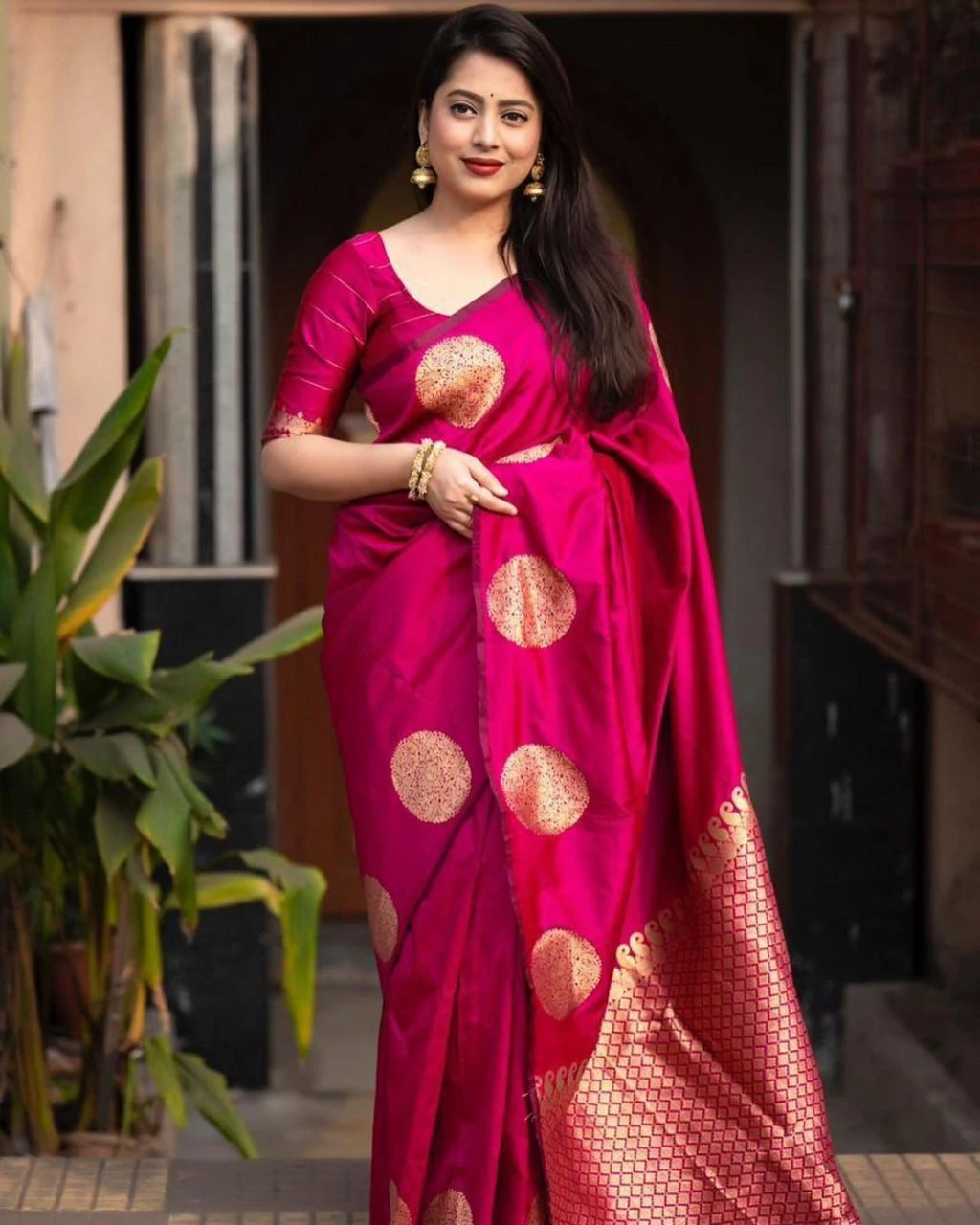 Fuchsia pink saree close view showing gold motifs, pleats and jacquard pallu edge