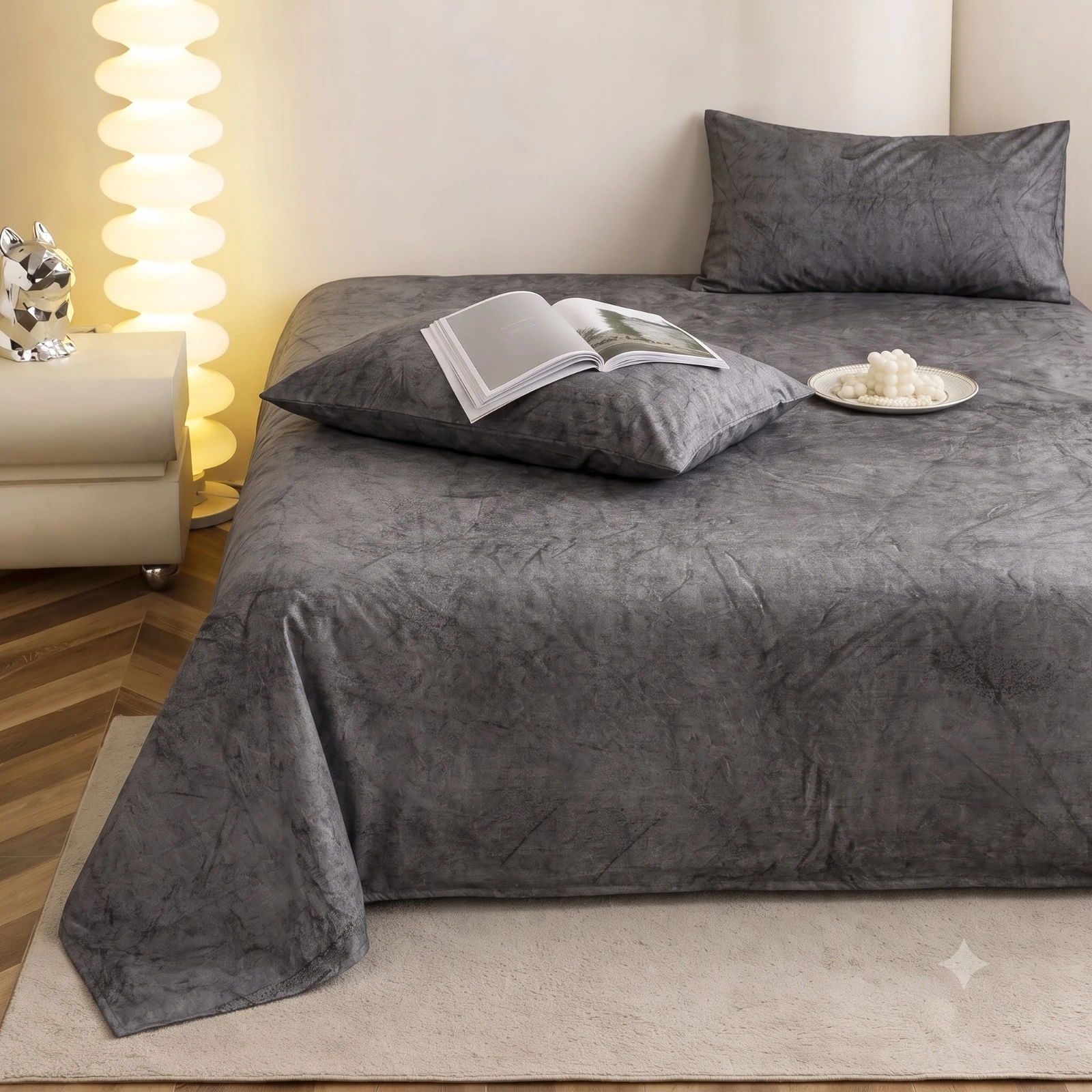 Side perspective of the grey textured bedding with matching pillows and soft drape over the bed edge