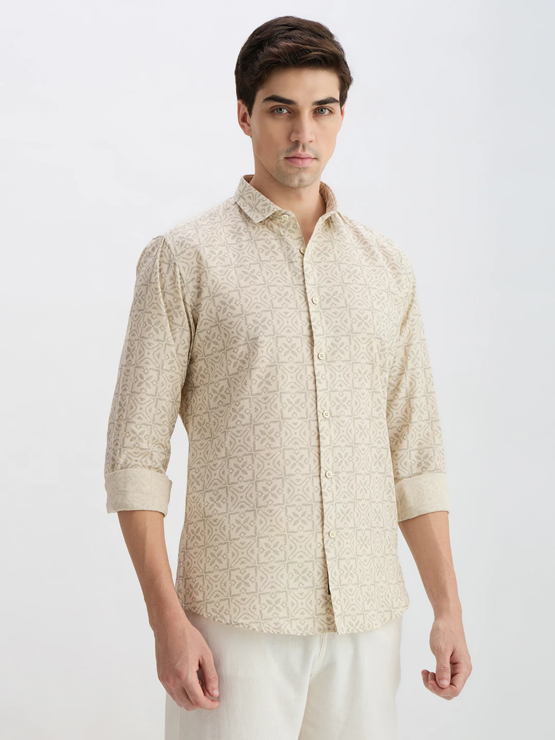 Angled front view of the shirt with rolled cuffs, highlighting the soft beige geometric pattern
