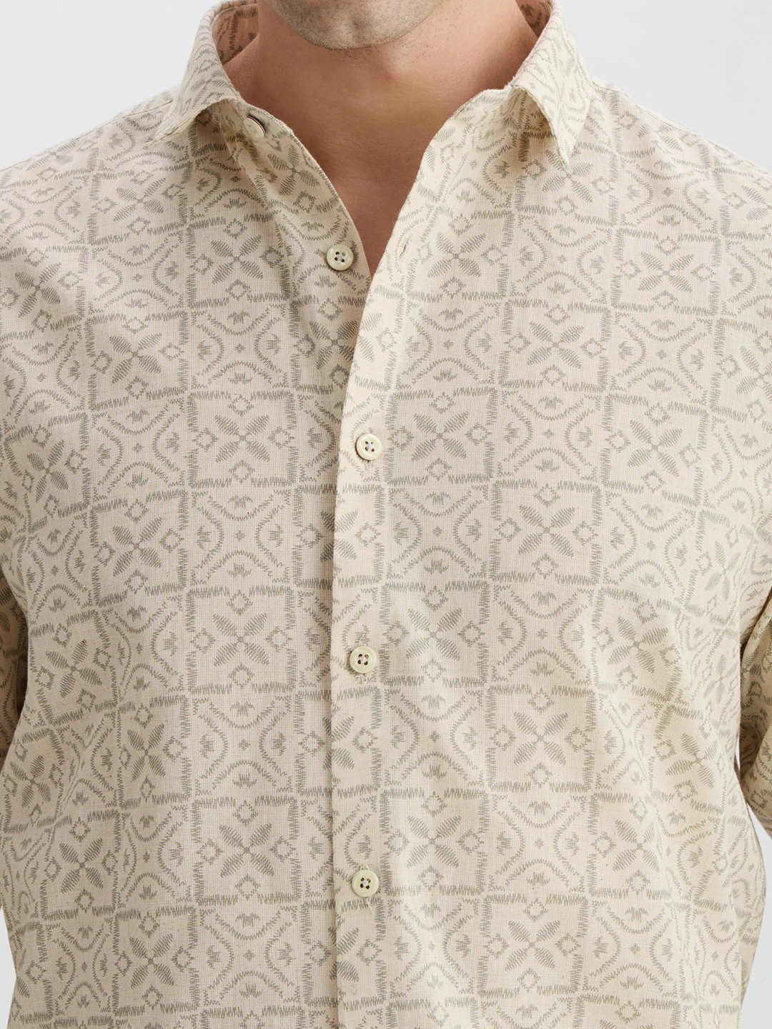 Close-up of collar, buttons, and geometric print detail on the beige fabric