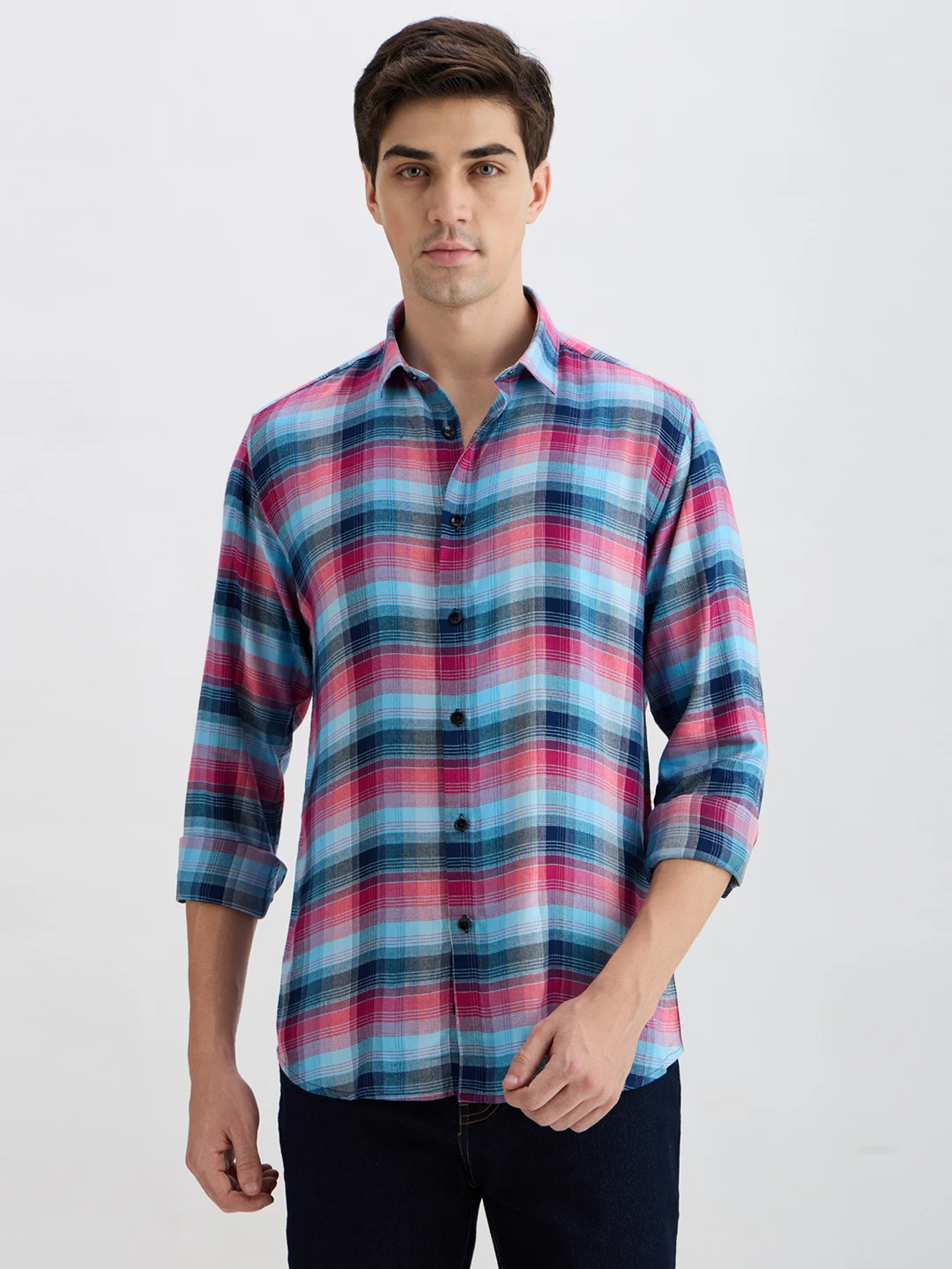 Front view of blue and pink plaid casual shirt worn with dark jeans, sleeves rolled to forearms