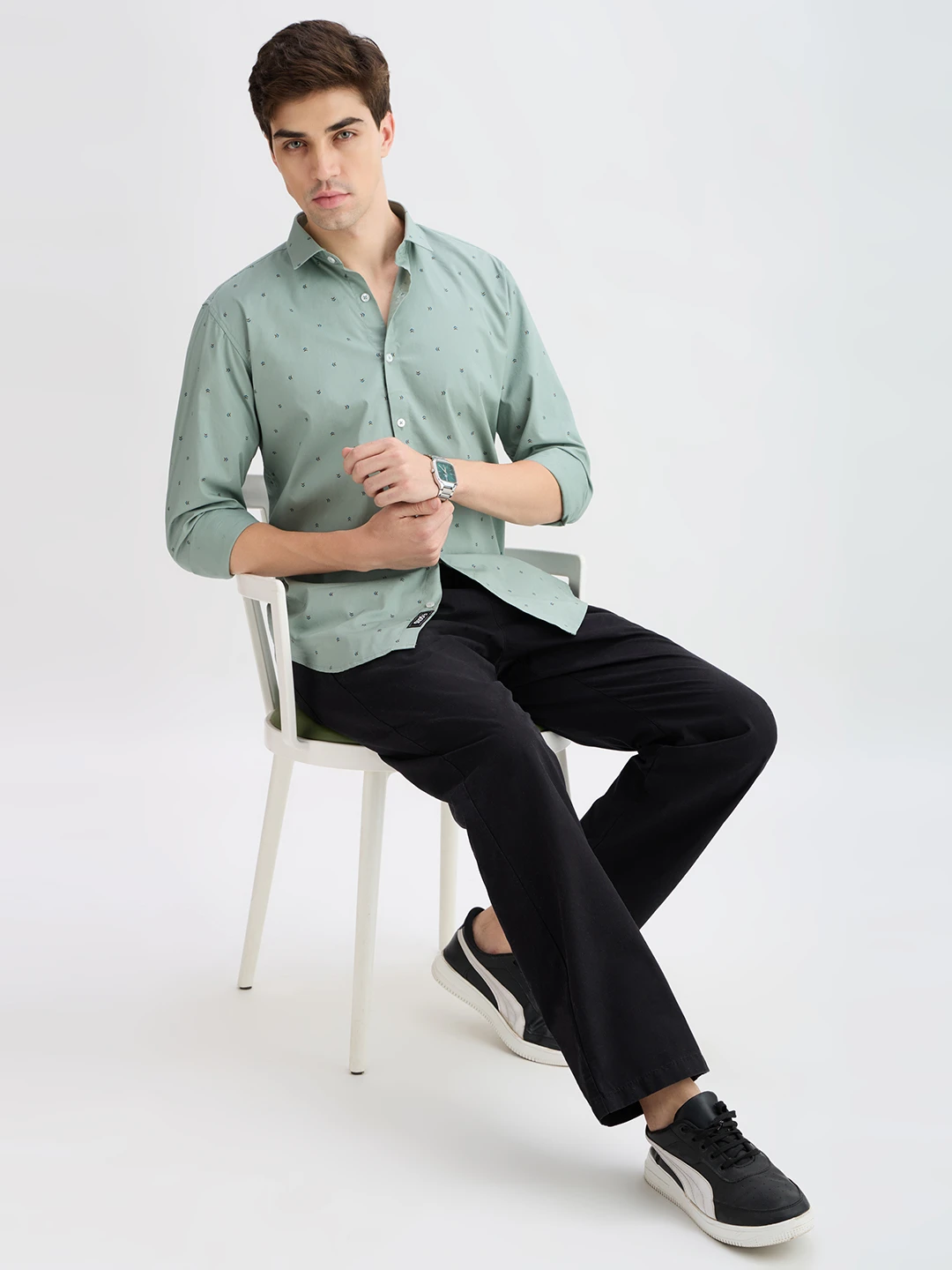 Seated full-body styling view with the shirt paired with black trousers