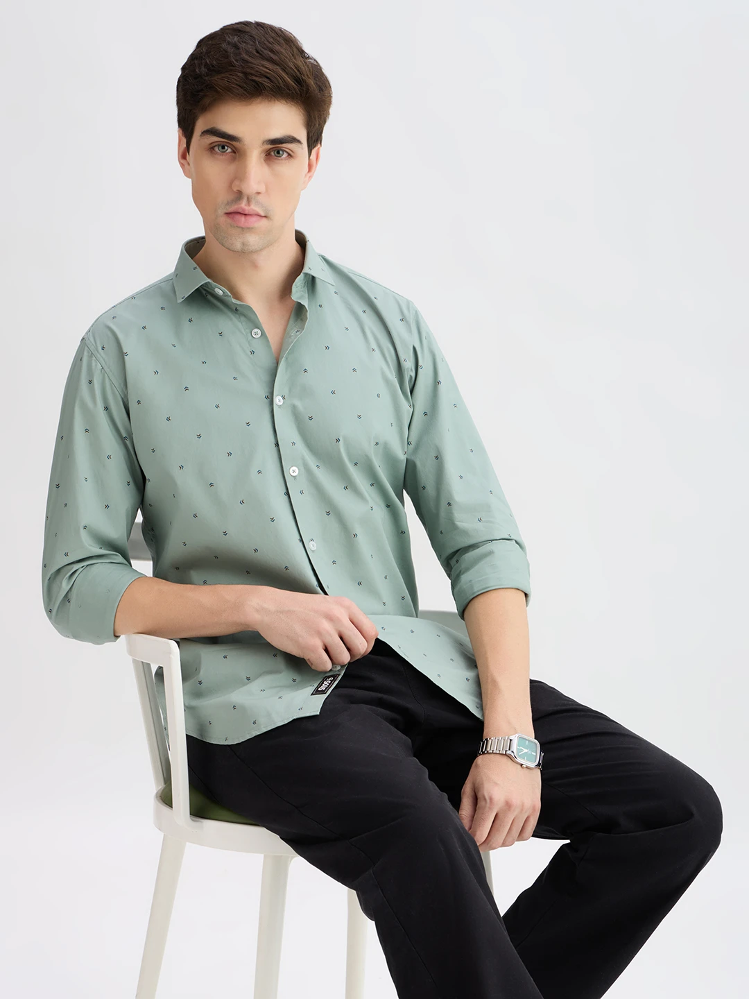 Closer seated angle highlighting the shirt drape, cuff fold and front print