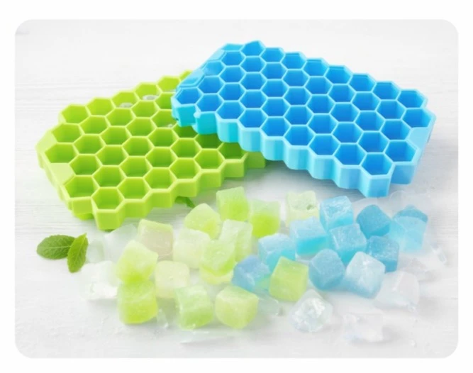 Two empty hexagon silicone trays in blue and green with loose ice cubes scattered in front
