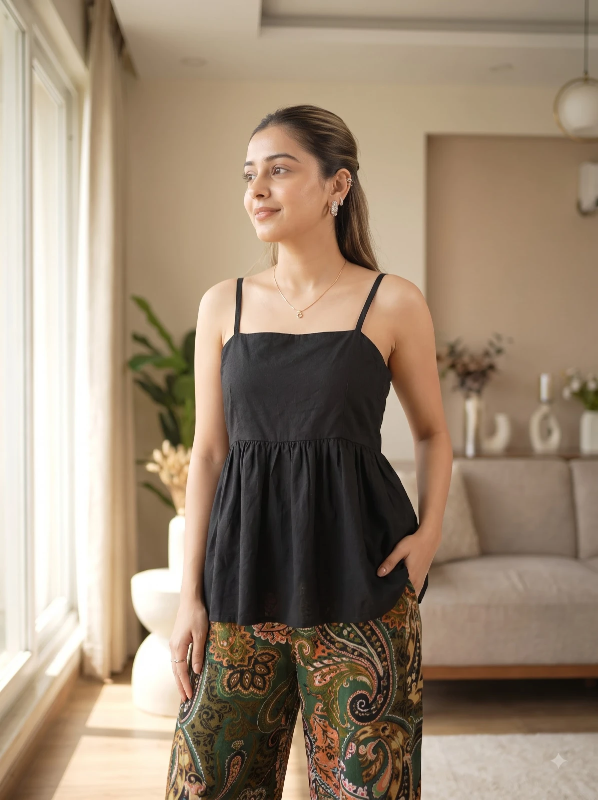 Window-lit front pose of the black sleeveless top showing relaxed fit and square neckline