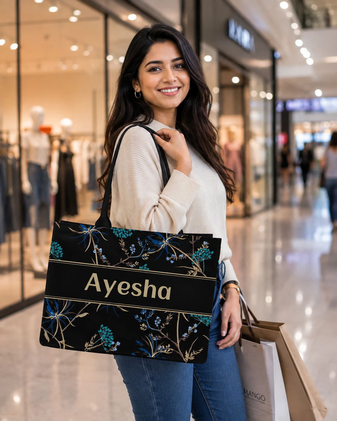 Customized black floral tote carried in mall, with Ayesha name printed across center stripe