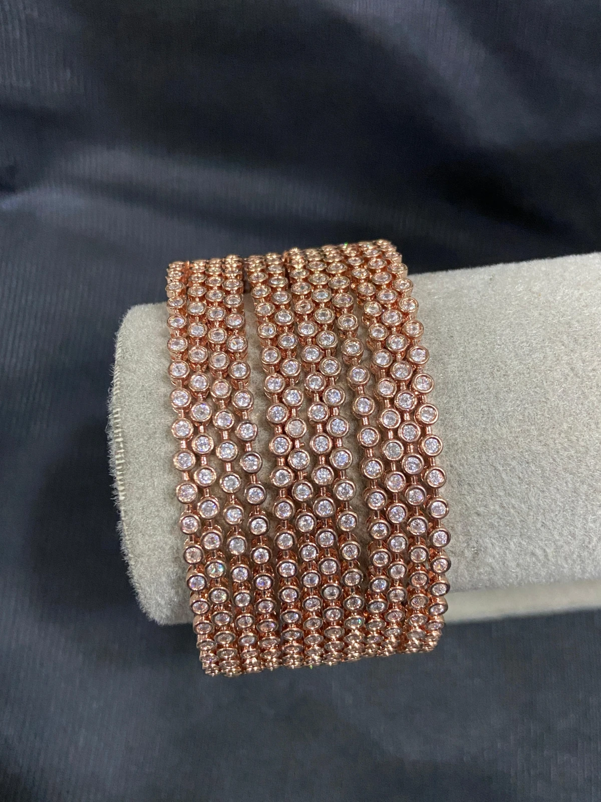 Rose gold-tone multi-row crystal wrap bracelet coiled on a velvet display cushion