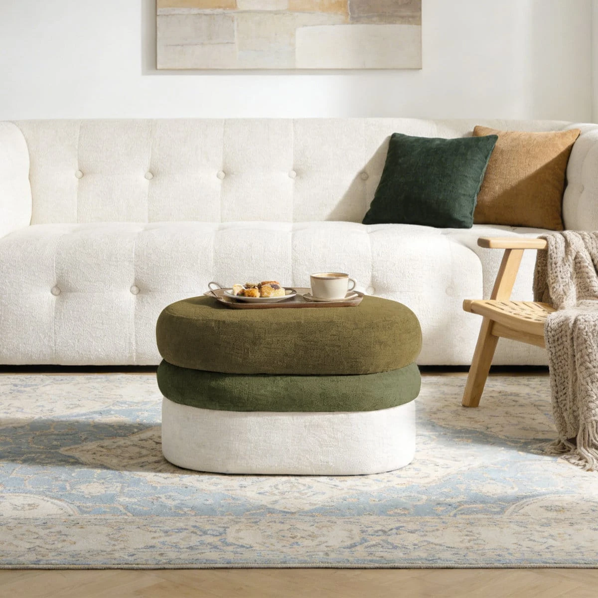 Ottoman styled as a coffee table with a tray, cup, and snacks in a living room setting