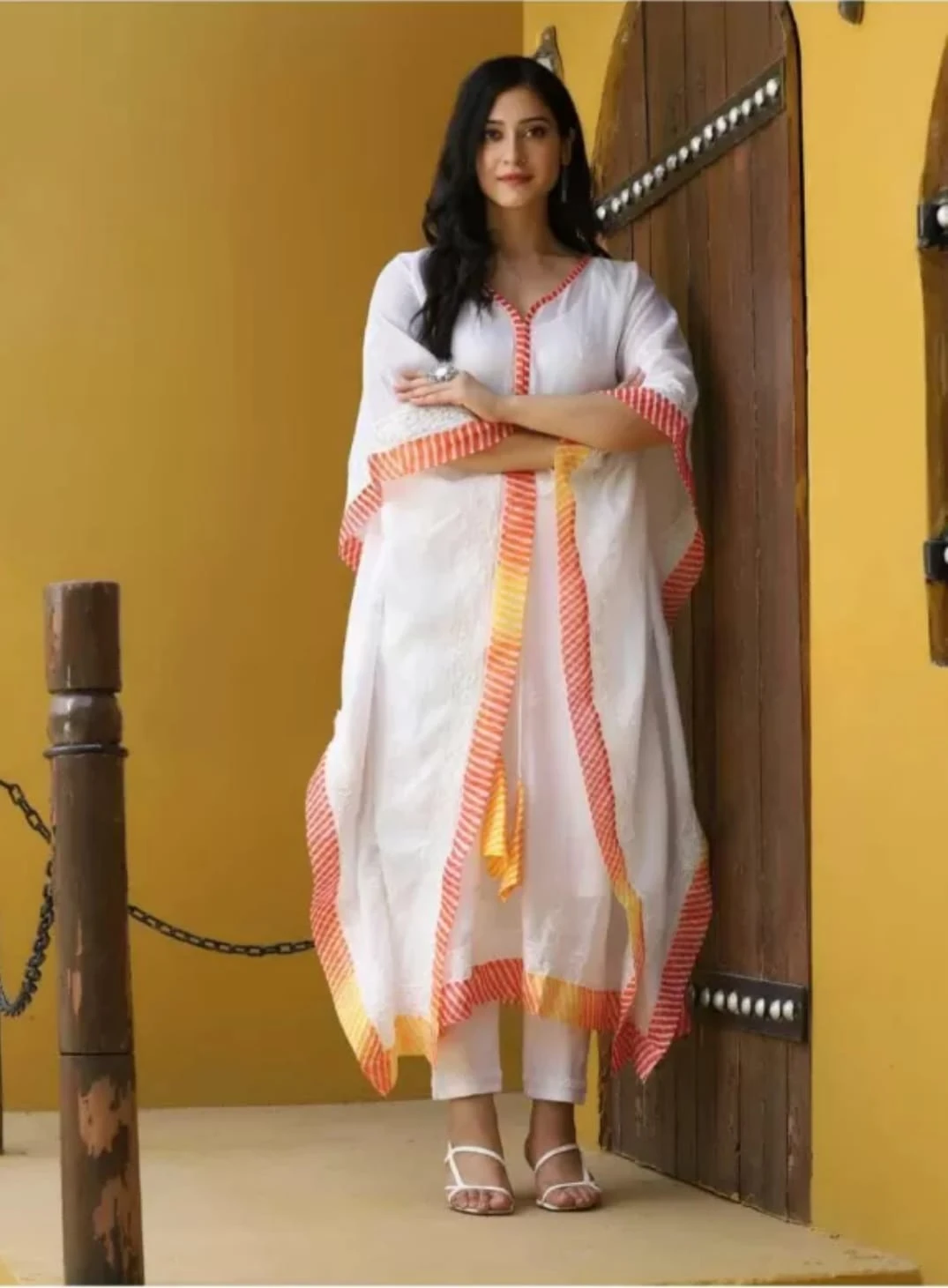 Full front view of the flowy white kaftan showing wide drape, tasseled tie and contrast striped border