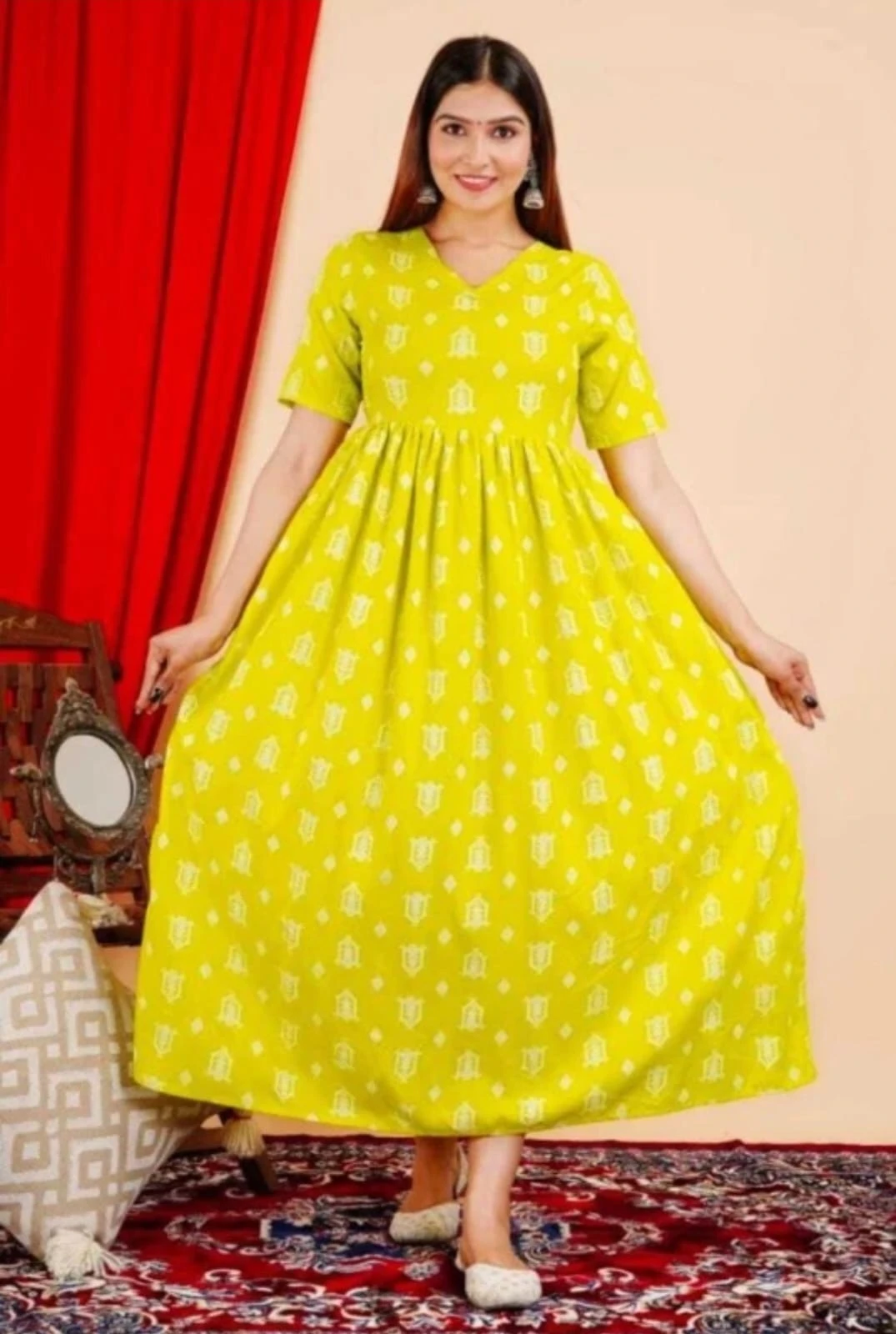 Yellow printed maxi dress with short sleeves and V-neck shown front view with gathered waist indoors
