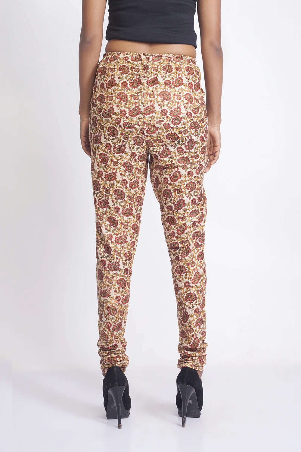 Back view of cream paisley leggings with elastic waist and gathered hems, worn with black stiletto heels