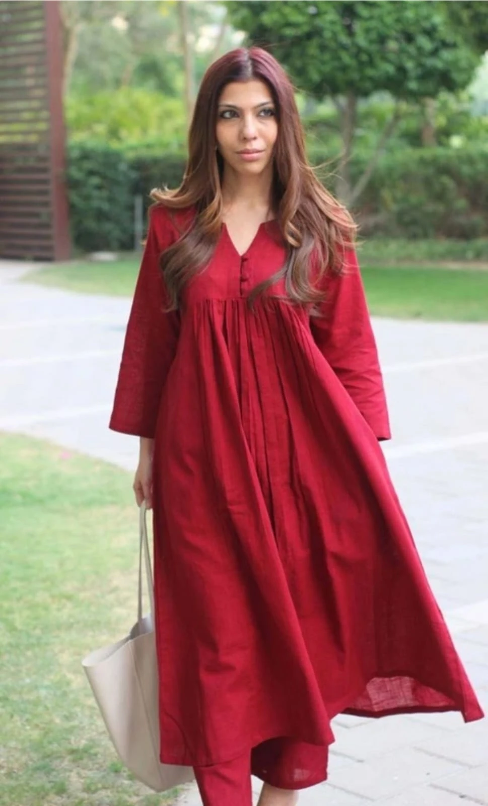 Angled front view showing the flowy flare, V-slit neckline and pleated yoke of the maroon kurta set