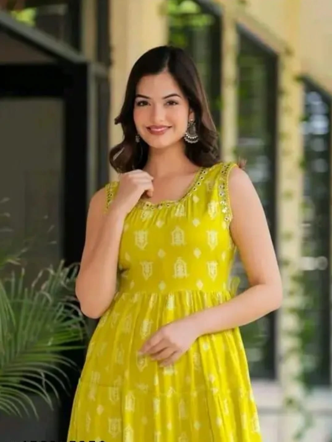 Sleeveless yellow printed maxi dress with tiered flared hem shown in a full-length outdoor front view