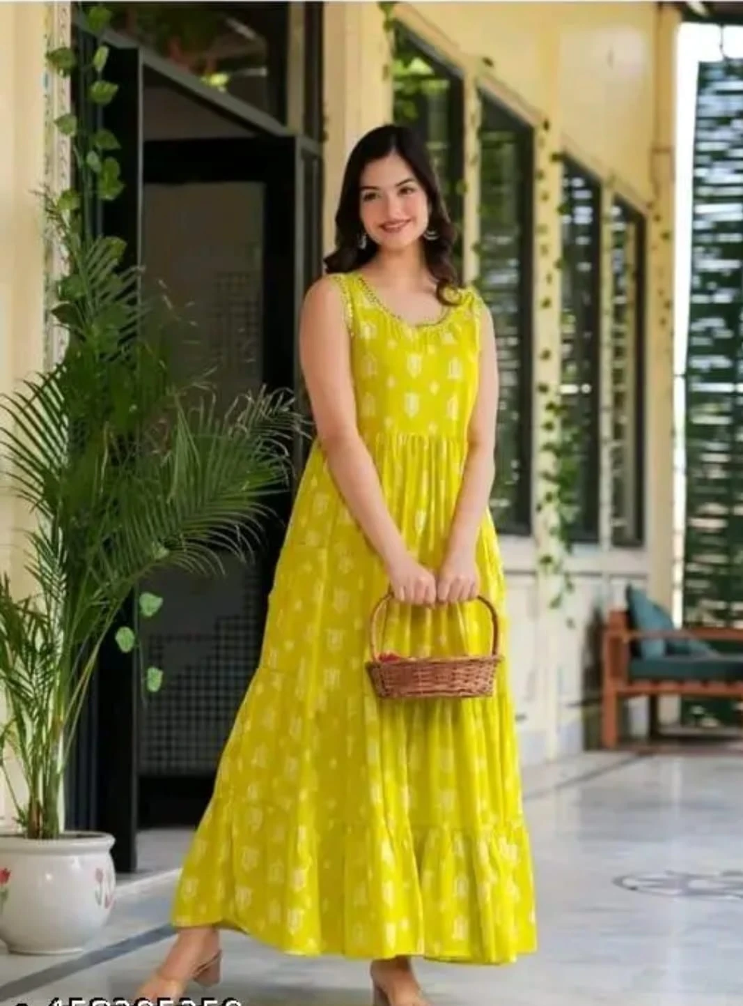 Sleeveless yellow printed maxi dress with tiered flared hem shown in a full-length outdoor front view