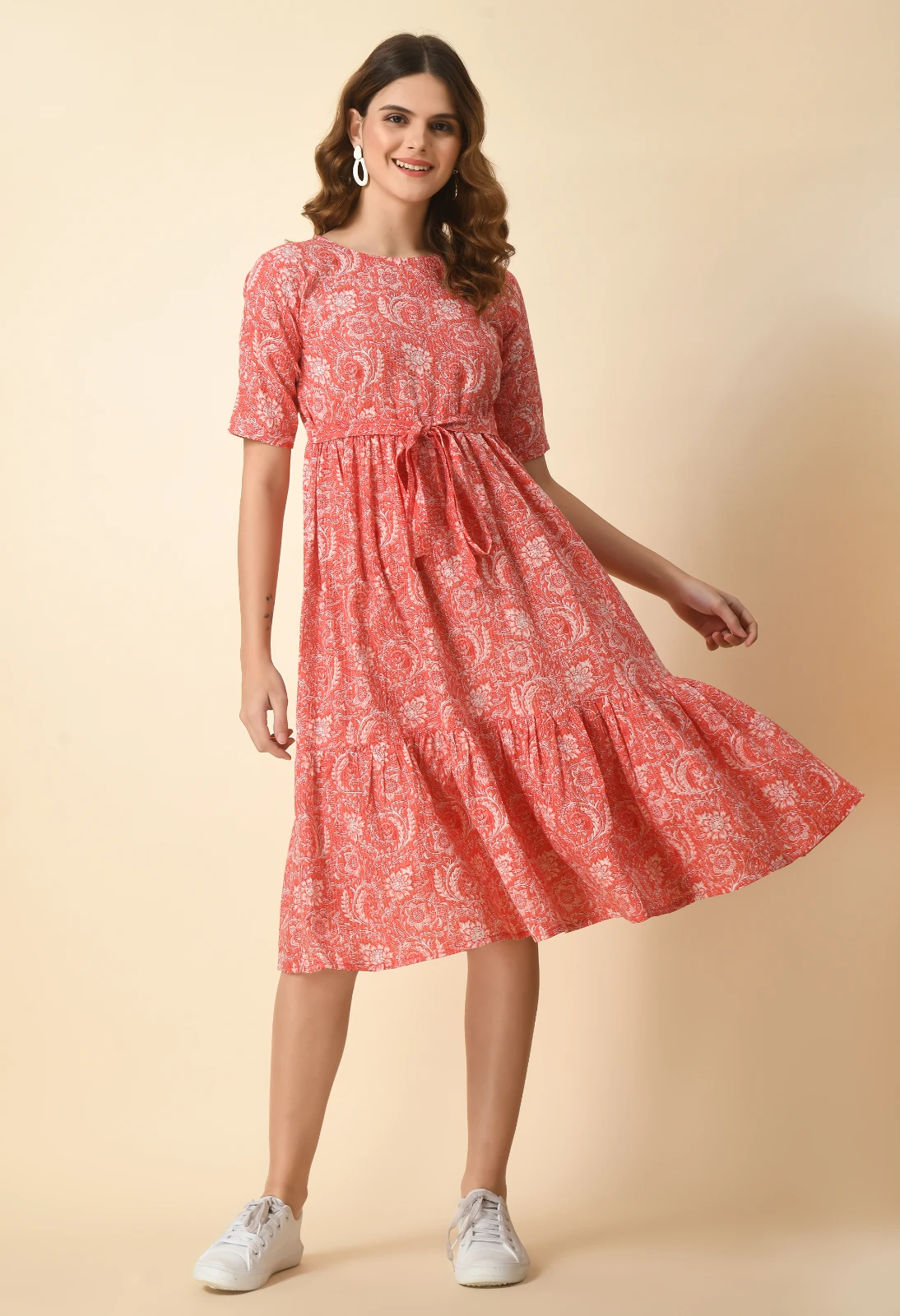 Coral printed dress shown in motion, highlighting the flared skirt and ruffled lower tier