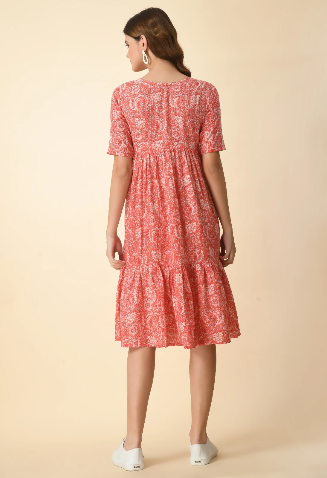 Back view of the coral midi dress with elbow sleeves, gathered waist seam and tiered skirt
